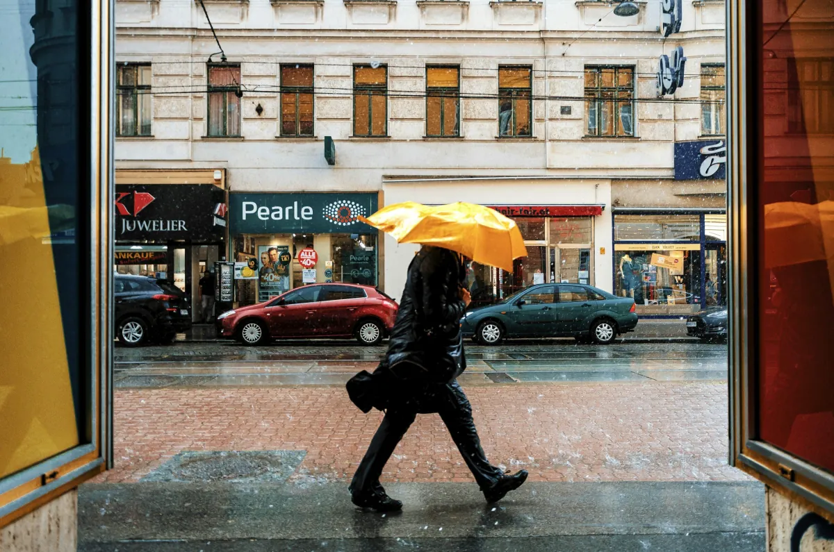 A person with a yellow umbrella on a rainy street